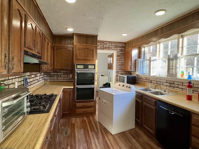 kitchen featuring dark wood-type flooring, black appliances, sink, a textured ceiling, and washer / clothes dryer