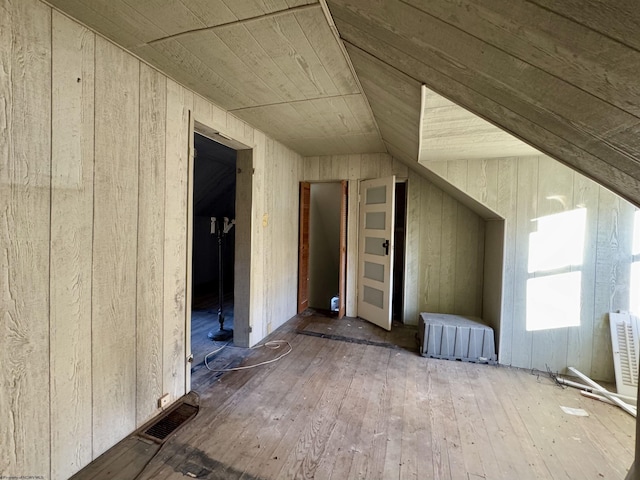 bonus room with hardwood / wood-style flooring, lofted ceiling, and wood walls