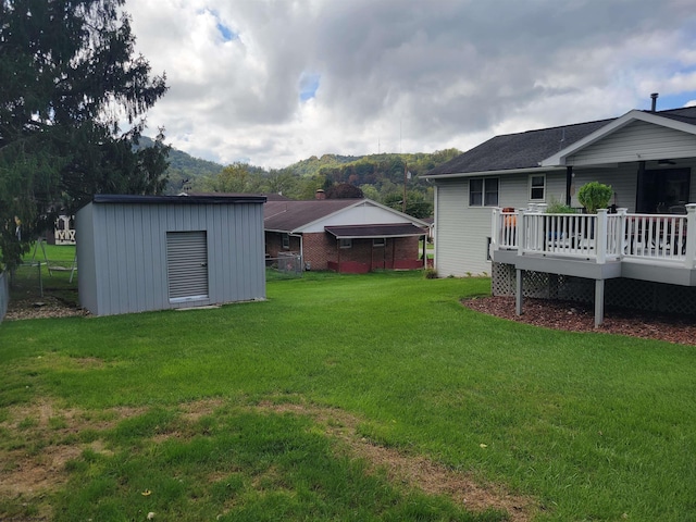 view of yard featuring a storage shed and a deck with mountain view