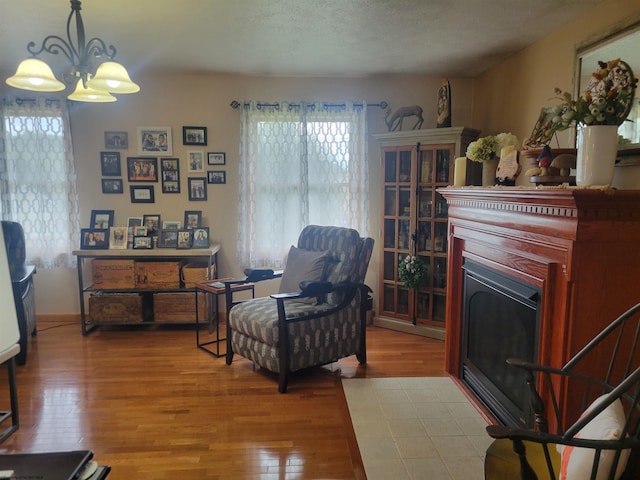 living area with light hardwood / wood-style flooring, a healthy amount of sunlight, a textured ceiling, and an inviting chandelier