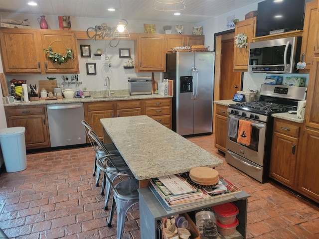 kitchen with sink, stainless steel appliances, a kitchen breakfast bar, pendant lighting, and a kitchen island