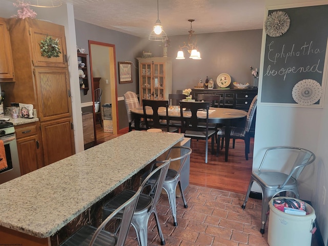 kitchen featuring a center island, light stone countertops, decorative light fixtures, wood-type flooring, and a chandelier