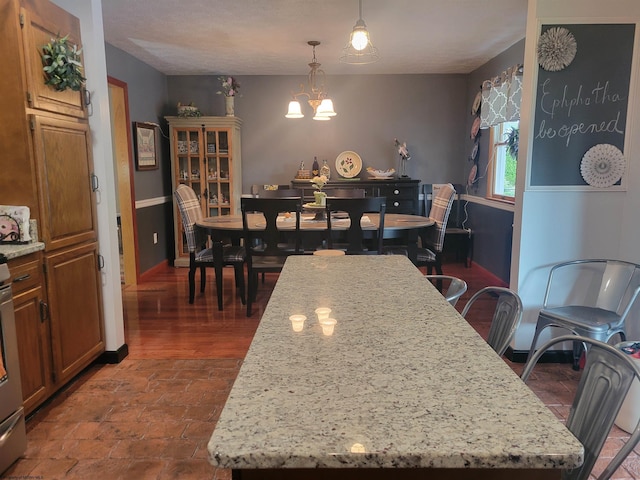 kitchen featuring pendant lighting, a notable chandelier, a center island, and light stone counters