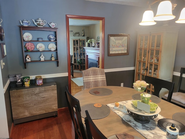 dining area featuring a chandelier, a fireplace, and dark wood-type flooring