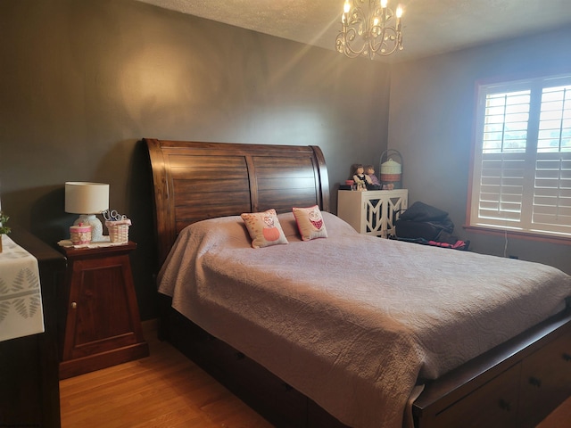 bedroom featuring light wood-type flooring and an inviting chandelier