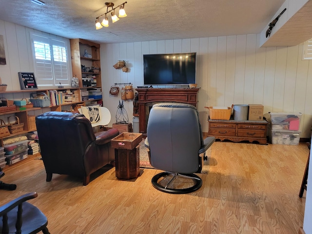 living room featuring a textured ceiling, light wood-type flooring, and wooden walls