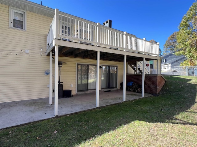 back of house featuring a wooden deck, a patio area, and a yard