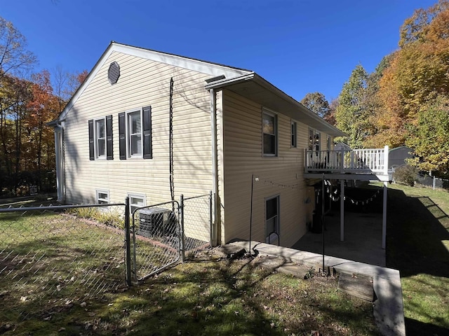 view of side of property featuring central air condition unit, a lawn, and a deck