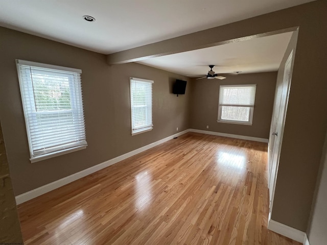 empty room featuring ceiling fan, beamed ceiling, and light hardwood / wood-style floors