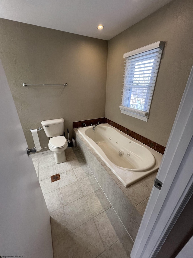 bathroom featuring tile patterned flooring, a relaxing tiled tub, and toilet