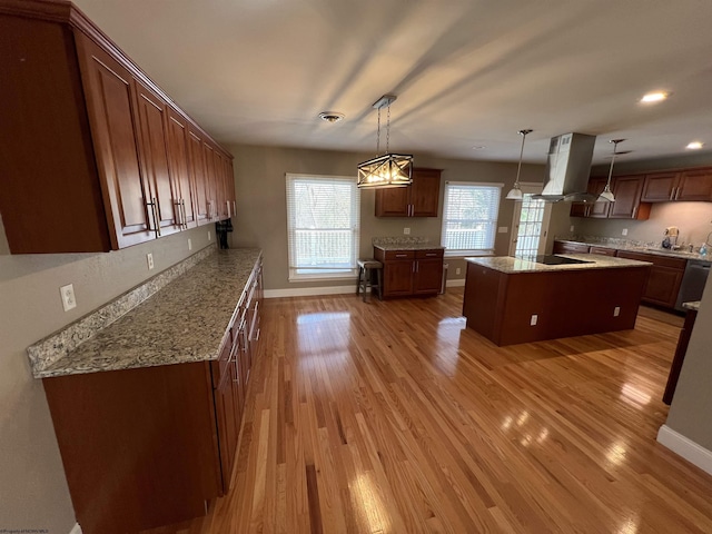 kitchen with light hardwood / wood-style flooring, decorative light fixtures, island range hood, black electric stovetop, and a kitchen island