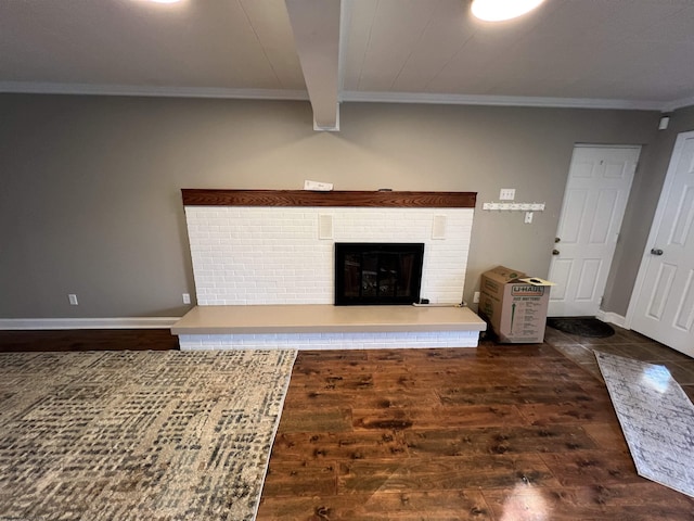 unfurnished living room featuring beam ceiling, dark hardwood / wood-style flooring, ornamental molding, and a brick fireplace