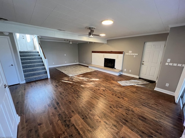 unfurnished living room featuring ceiling fan, dark hardwood / wood-style flooring, a fireplace, and crown molding