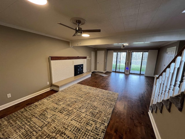 unfurnished living room with dark hardwood / wood-style floors, ceiling fan, crown molding, and a fireplace