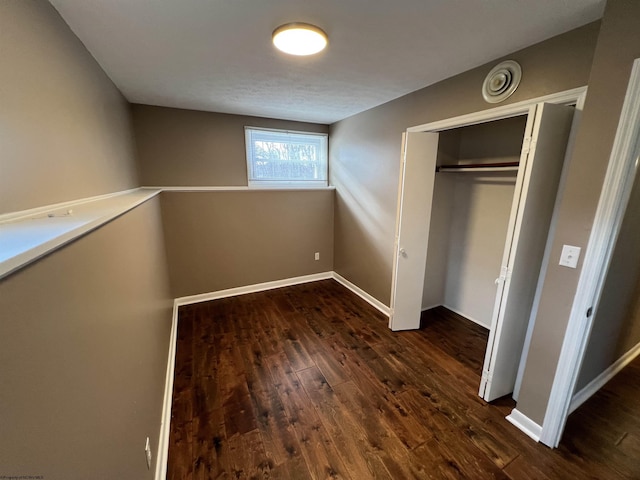 unfurnished bedroom featuring dark hardwood / wood-style flooring and a closet