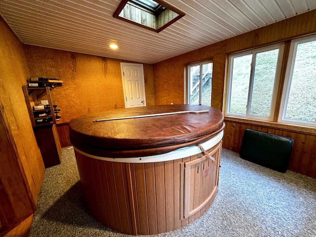 bar with carpet, wood walls, a skylight, and a hot tub