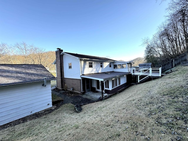 rear view of house featuring a deck and a yard