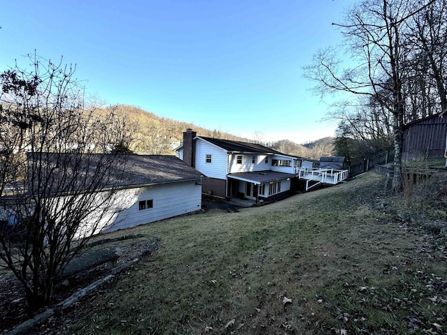 rear view of property featuring a yard and a deck with mountain view