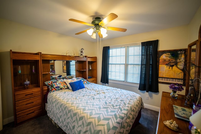 bedroom with ceiling fan, baseboards, and dark colored carpet