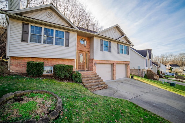 split foyer home with brick siding, a front yard, a chimney, a garage, and driveway