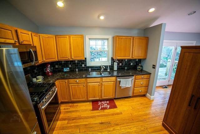 kitchen with light wood-type flooring, a sink, backsplash, recessed lighting, and appliances with stainless steel finishes