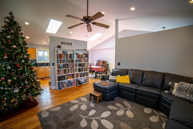 living room with lofted ceiling with skylight, recessed lighting, light wood-style floors, and visible vents