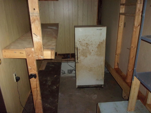 interior space with white fridge and wood walls