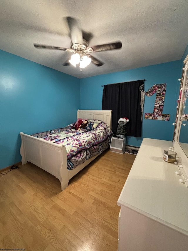 bedroom with ceiling fan, light hardwood / wood-style floors, and a textured ceiling