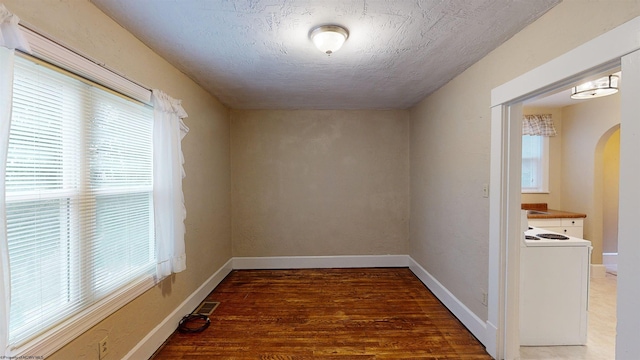 unfurnished room with a textured ceiling, dark hardwood / wood-style flooring, and a wealth of natural light