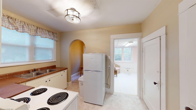 kitchen featuring white cabinetry, sink, and white appliances