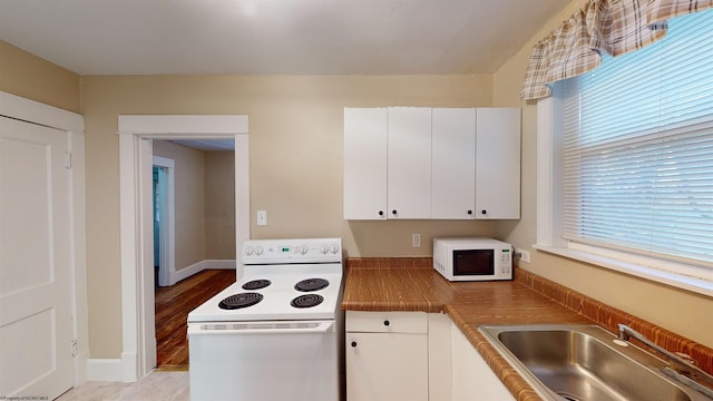 kitchen with light hardwood / wood-style floors, white cabinetry, white appliances, and sink