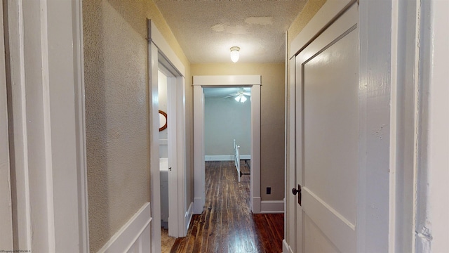 hallway featuring dark hardwood / wood-style flooring and a textured ceiling