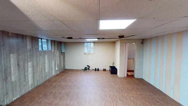 basement with a paneled ceiling, hardwood / wood-style flooring, and wooden walls