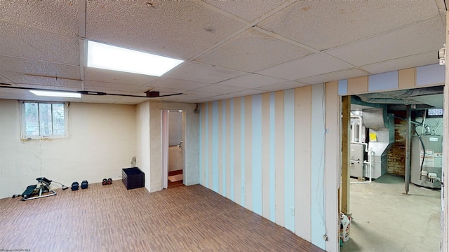 basement featuring a paneled ceiling and gas water heater