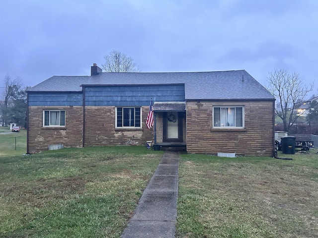 view of front of house with roof with shingles, a front lawn, and a chimney