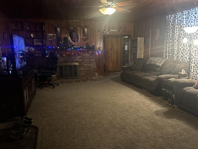 living room with carpet, a brick fireplace, built in shelves, ceiling fan, and wooden walls