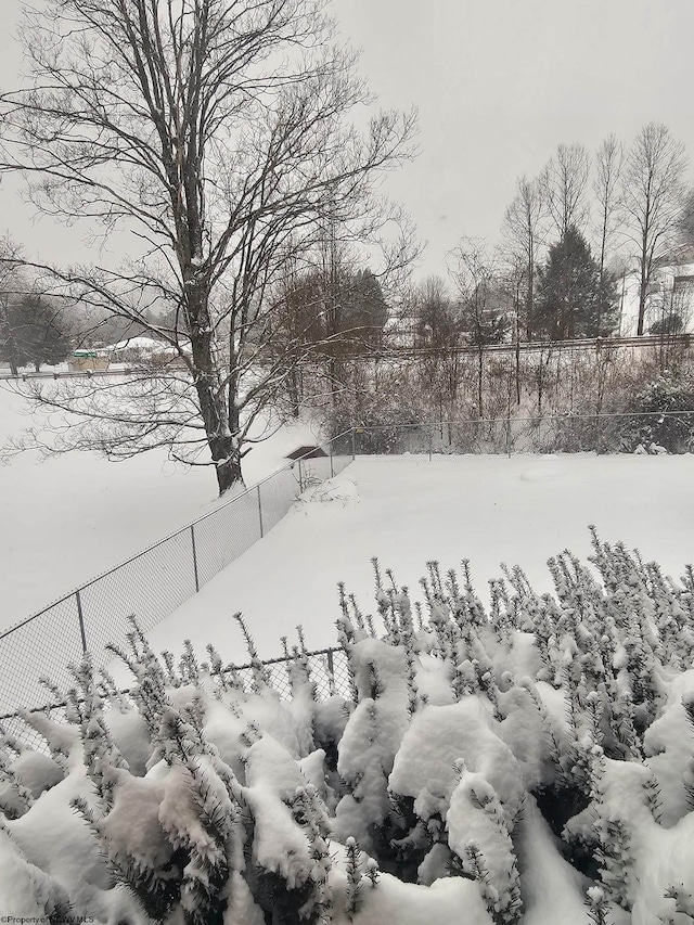 snowy yard with a fenced backyard