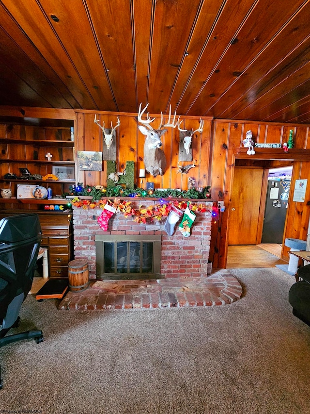 carpeted living room with wood ceiling, wooden walls, and a fireplace