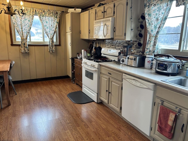 kitchen featuring white appliances, light wood-style flooring, backsplash, light countertops, and a sink