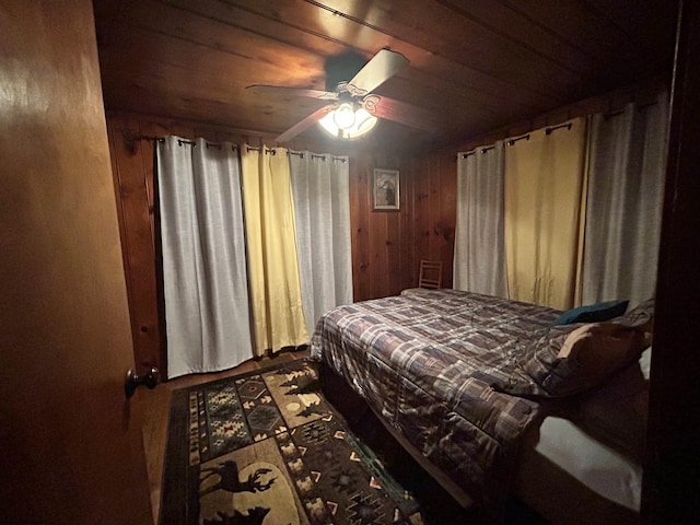 bedroom featuring wooden ceiling, wooden walls, and a ceiling fan