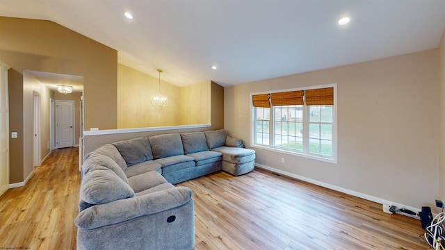 living room with a notable chandelier, lofted ceiling, and light hardwood / wood-style flooring