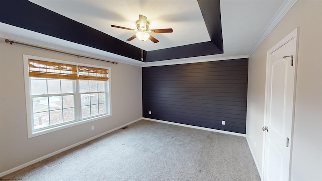 spare room featuring ceiling fan, light colored carpet, crown molding, and a tray ceiling