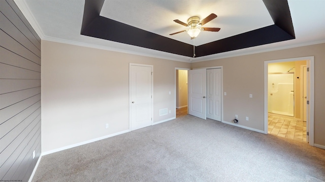 unfurnished bedroom featuring carpet, ceiling fan, crown molding, and a tray ceiling