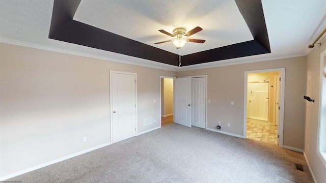 unfurnished bedroom featuring ceiling fan, a raised ceiling, light colored carpet, and crown molding