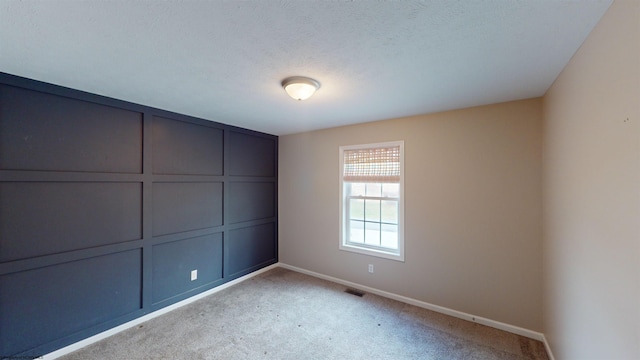 unfurnished room with a textured ceiling and light carpet