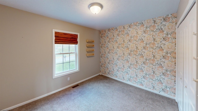 carpeted spare room with a textured ceiling