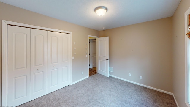 unfurnished bedroom featuring light carpet and a closet