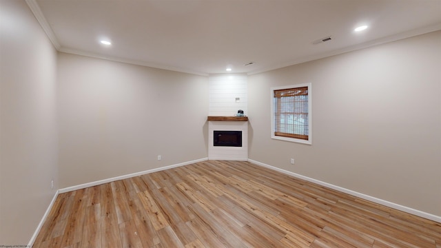 unfurnished living room with crown molding, a fireplace, and light wood-type flooring