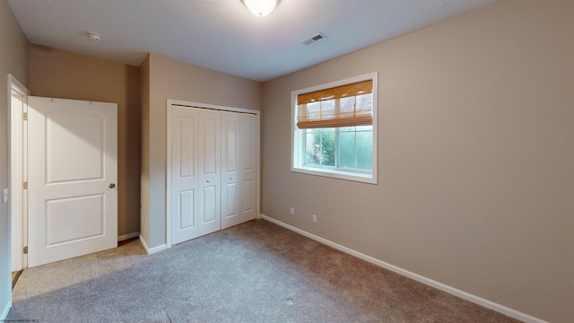 unfurnished bedroom with light carpet and a closet