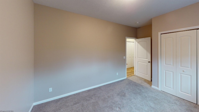 unfurnished bedroom featuring light colored carpet and a closet